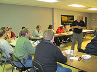 Employees sitting in a rectangular format listening to a speaker.