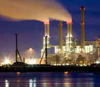 Industrial facility at twilight with smoke stacks billowing.