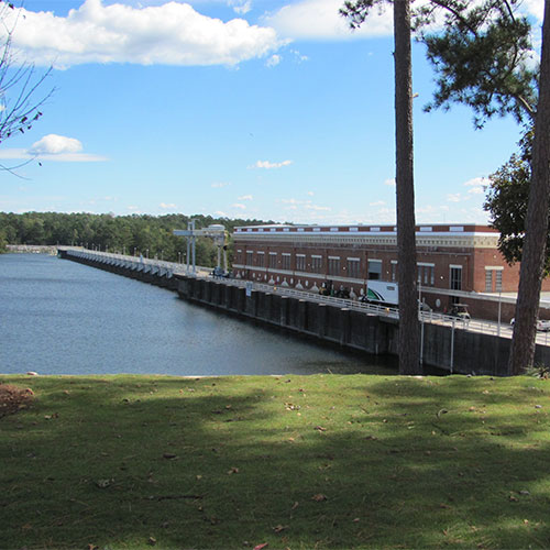Photo of a brick building adjacent to a dam holding back a body of water